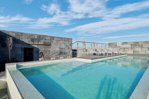 A swimming pool with clear blue water, surrounded by a stone wall and a glass railing. - Four Points by Sheraton Ciudad Juárez (Ciudad Juárez)