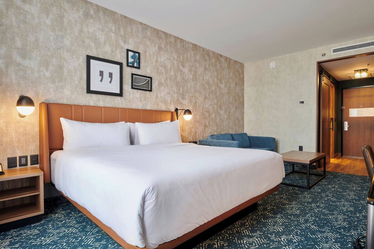 Ein Hotelzimmer mit einem großen Bett, einem kleinen Tisch, einer Couch und einer Wandlampe.