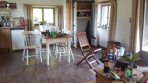 A rustic kitchen with wooden furniture, a dining area with white chairs, and a wooden chest of drawers. - Charming 1-Bed Cottage in The Hideout (La chapelle montbrandeix)