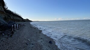 A pebbled beach with a rocky cliff and a wooden fence. - Luxury 3 bed mobile home on the sea (Southampton)
