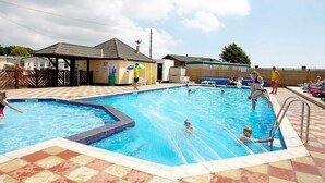 A swimming pool with tiled edges, a lifeguard tower, and a covered seating area. - Luxury 3 bed mobile home on the sea (Southampton)