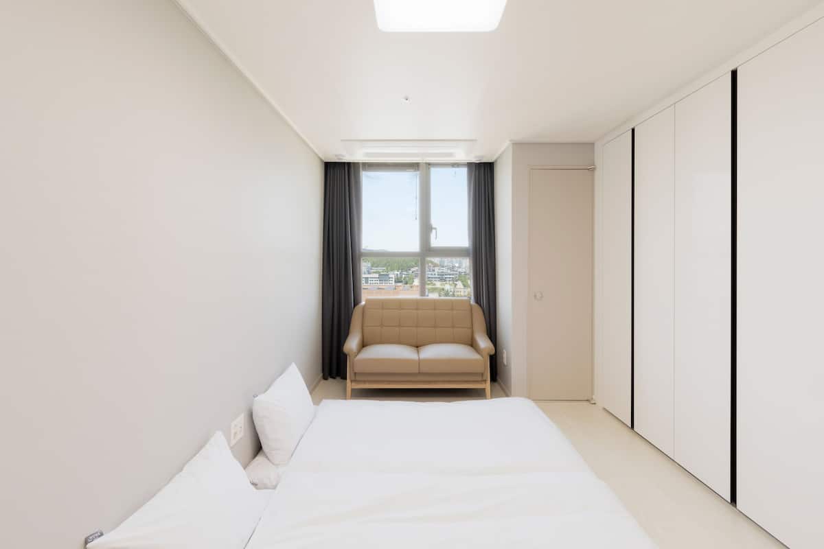 Une chambre d’hôtel moderne avec un grand lit, un canapé et une armoire.