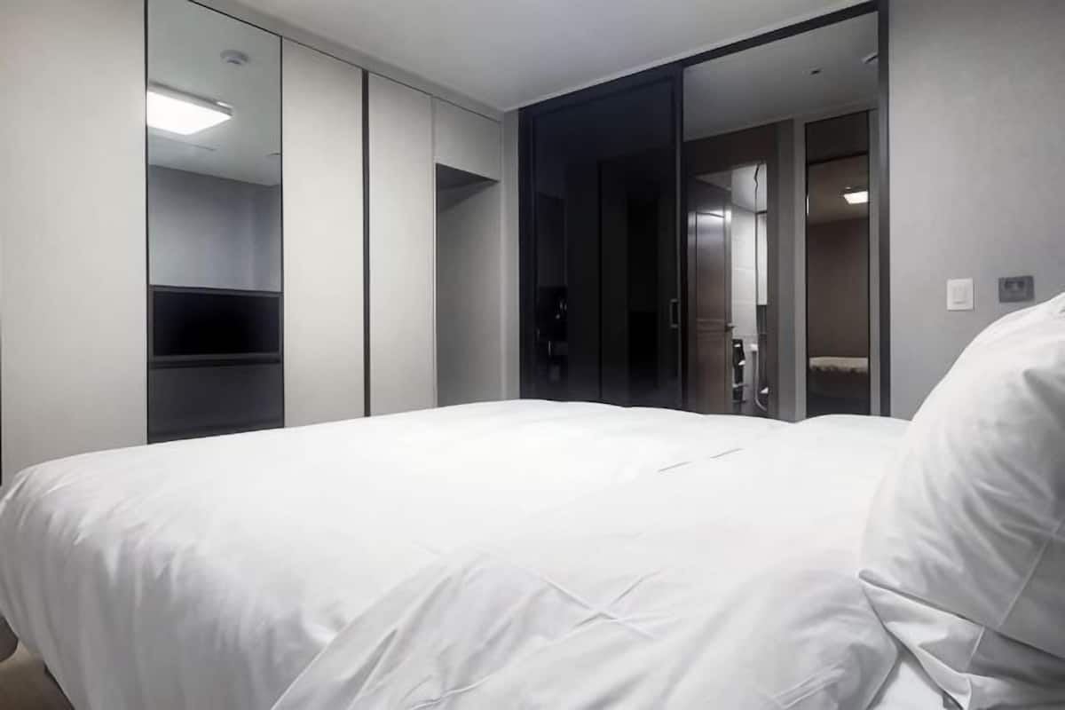 Une chambre d’hôtel avec un grand lit, une armoire, un miroir et une porte donnant sur une salle de bain.