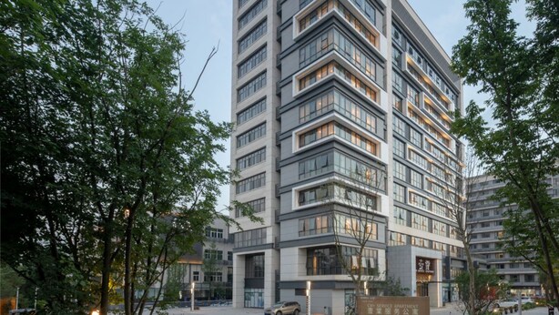 Un hotel de varios pisos con diseño moderno, que destaca por su entrada principal y un letrero que indica que se trata de apartamentos con servicios.