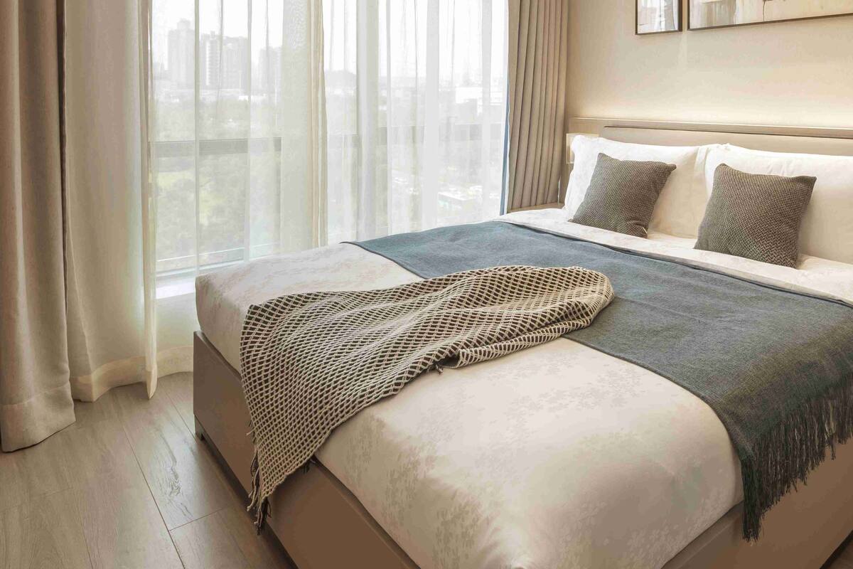 A modern hotel room with a large bed, a view of the city, and a cityscape visible through the window.
