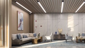 Un vestíbulo moderno con un sofá, sillas, piso de mármol y una pared con diseño de mármol.