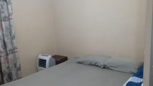 Ein Schlafzimmer mit einem Einzelbett, einem Nachttisch, einem Heizgerät und einem Vorhang.