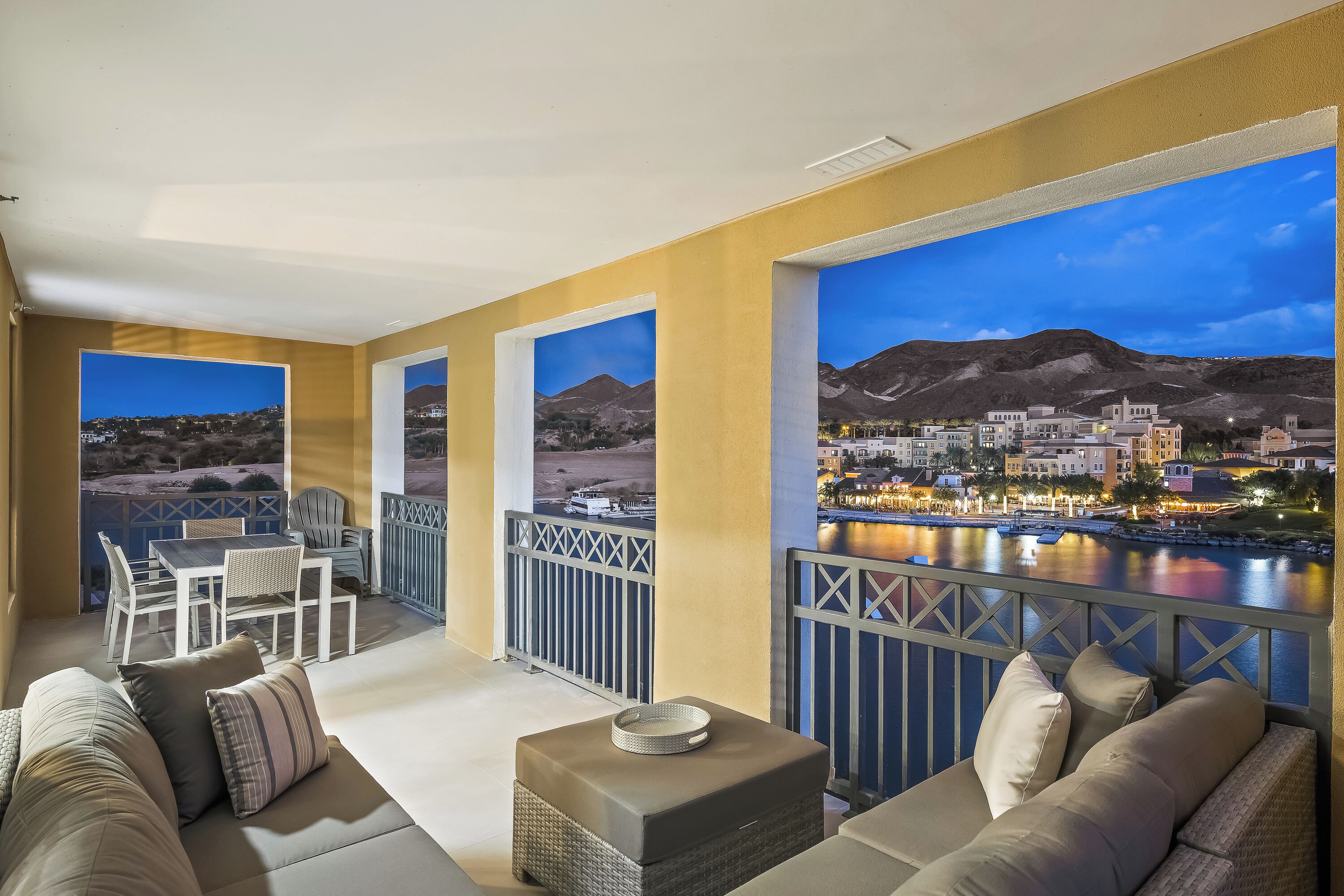 Een balkon met uitzicht op een stad aan het water in de schemering.