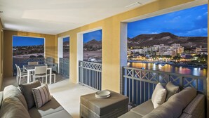 A balcony with a view of a town by the water at dusk.