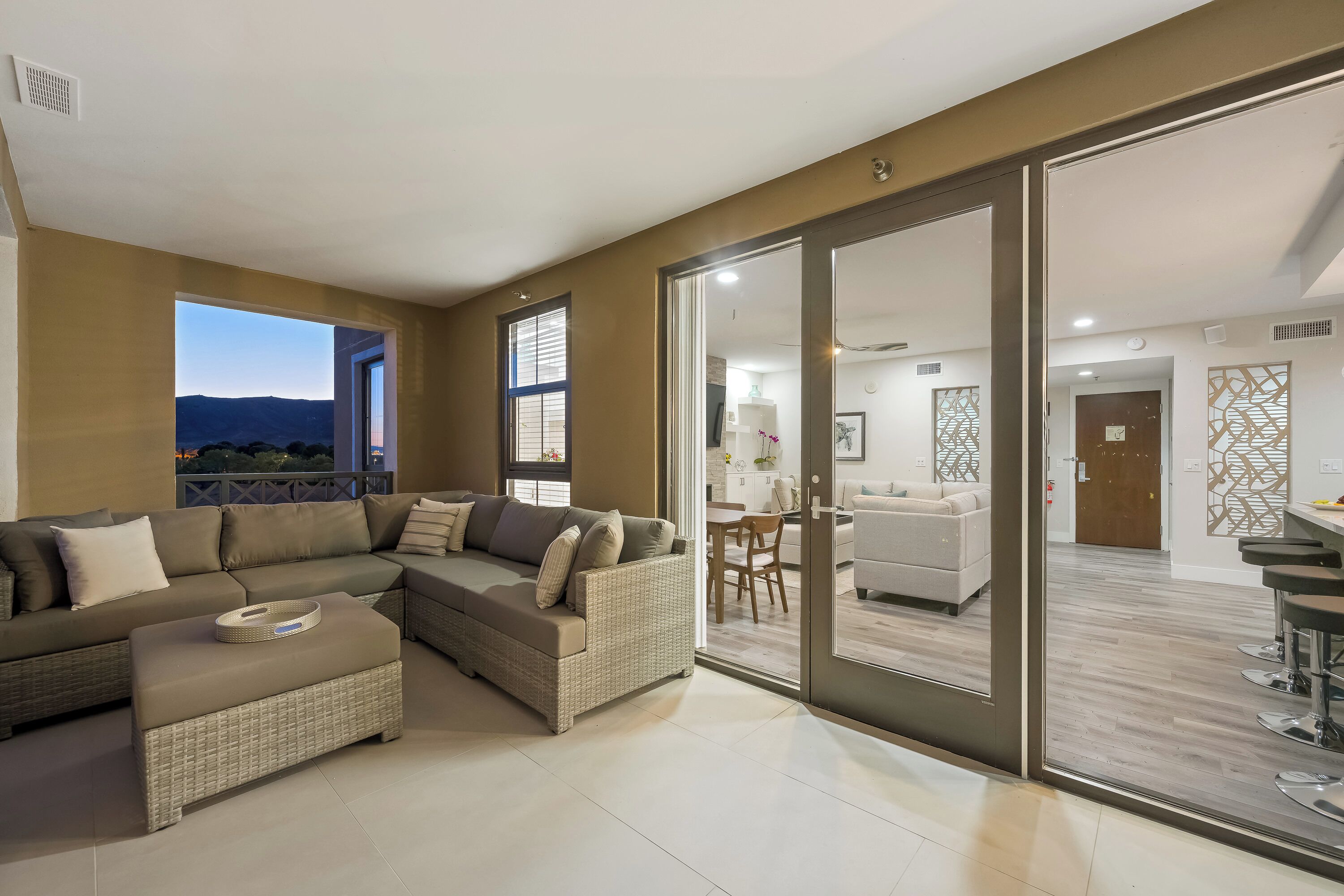 A modern living room with a sectional sofa, a small ottoman, and a dining area with a table and chairs.