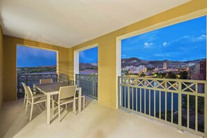 Un balcone con tavolo e sedie, con vista su una città e montagne.
