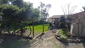 Un jardí amb una porta de fusta, una batea gran i un camí que condueix a una casa.