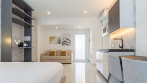 Una camera d'albergo moderna con un letto, un divano, angolo cottura e bagno.