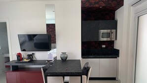 Una cocina moderna con microondas, televisor de pantalla plana y comedor con mesa y sillas.