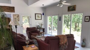 Ein geräumiges Wohnzimmer mit einem braunen Sofa, einem Glastisch und einem Deckenventilator.