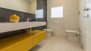 Ein modernes Badezimmer mit einem gelben Waschtisch, einem Bidet und einer Toilette.
