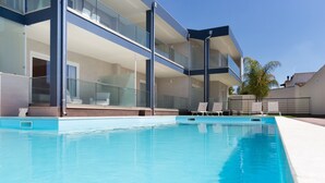 Ein moderner Poolbereich mit Glasgeländern, Liegestühlen und einem kühlen, blauen Pool.