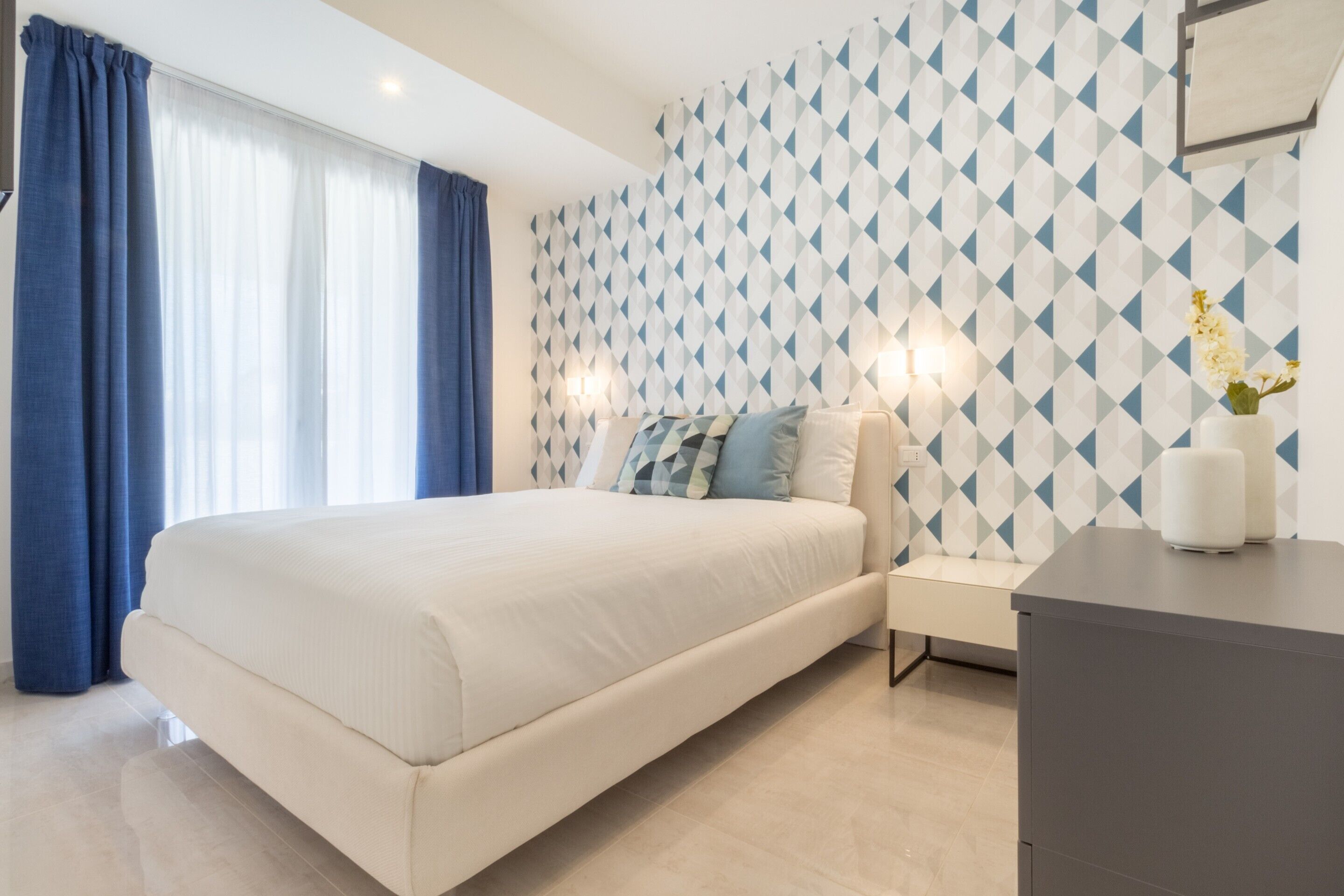 Une chambre à coucher moderne avec un grand lit, une table de chevet et une commode.