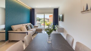 Una sala de estar moderna con un sofá, una mesa de comedor y un televisor montado en la pared.