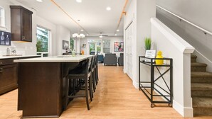A spacious kitchen with a central island, dark wooden cabinets, and a modern design. - Wondrous Woodstock Townhouse, Huge Open Floor Plan, Custom Décor and Artwork, Four Miles to Portland (Portland)