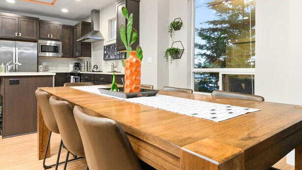 A modern kitchen with dark wooden cabinets, stainless steel appliances, and a large window providing a view of trees. - Wondrous Woodstock Townhouse, Huge Open Floor Plan, Custom Décor and Artwork, Four Miles to Portland (Portland)