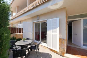 A patio with a round table and chairs, a sliding glass door, and a stone wall.