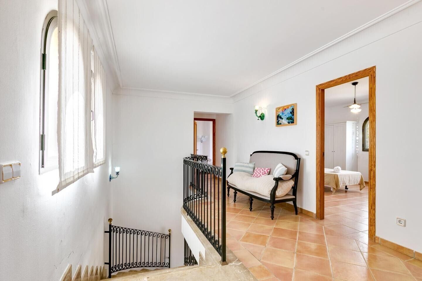 Una escala que condueix a una habitació amb un llit, una cadira i un quadre a la paret.