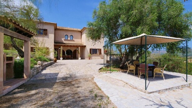 A villa with a stone pathway leading to a covered patio with outdoor furniture. - Chalet "Sa Corbaia Nova" with Mountain View, Pool, Wi-Fi, Terraces & Garden (Artà)
