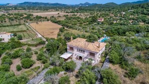 A villa with a tiled roof, surrounded by greenery and hills. - Chalet "Sa Corbaia Nova" with Mountain View, Pool, Wi-Fi, Terraces & Garden (Artà)