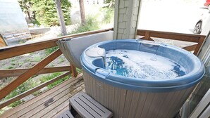 Ett bubbelbad på ett trädäck med ett trästaket och ett litet trappsteg som leder upp till det.