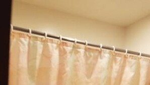 Une salle de bain avec un rideau de douche, un porte-serviettes et une petite poubelle.