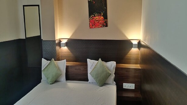 Habitación de hotel con cama, dos almohadas, cabecero, una obra de arte en la pared y mesita de noche.