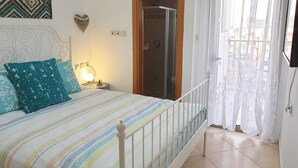 A bedroom with a bed, nightstand, and a bathroom door. - shohamseaview (Eilat)