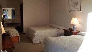 A hotel room with two beds, a desk, a chair, a lamp, and a framed picture on the wall. - Unity Lodge Suite 9 (Golconda)