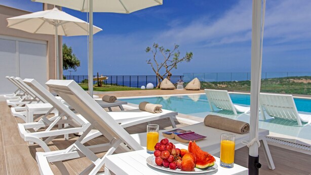 A poolside area with lounge chairs, umbrellas, and a table with fruit and drinks. - Luxury Villa Oasis, 11 bedrooms, Private Heated Pool & Jacuzzi (Rethymno)