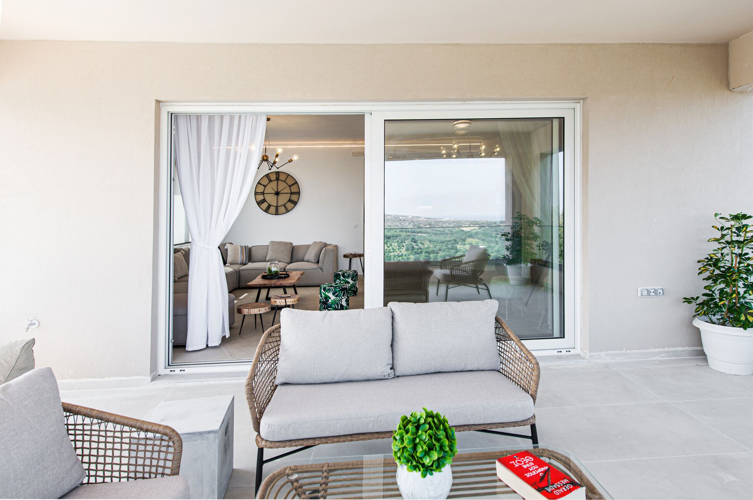 A modern living room with a sofa, chairs, a coffee table, and a large window offering a view of the outdoors.