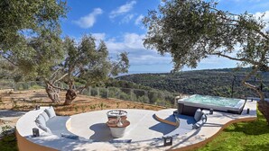 A circular outdoor seating area with a hot tub, surrounded by trees and a scenic view of hills. - Luxury Villa Oasis, 11 bedrooms, Private Heated Pool & Jacuzzi (Rethymno)