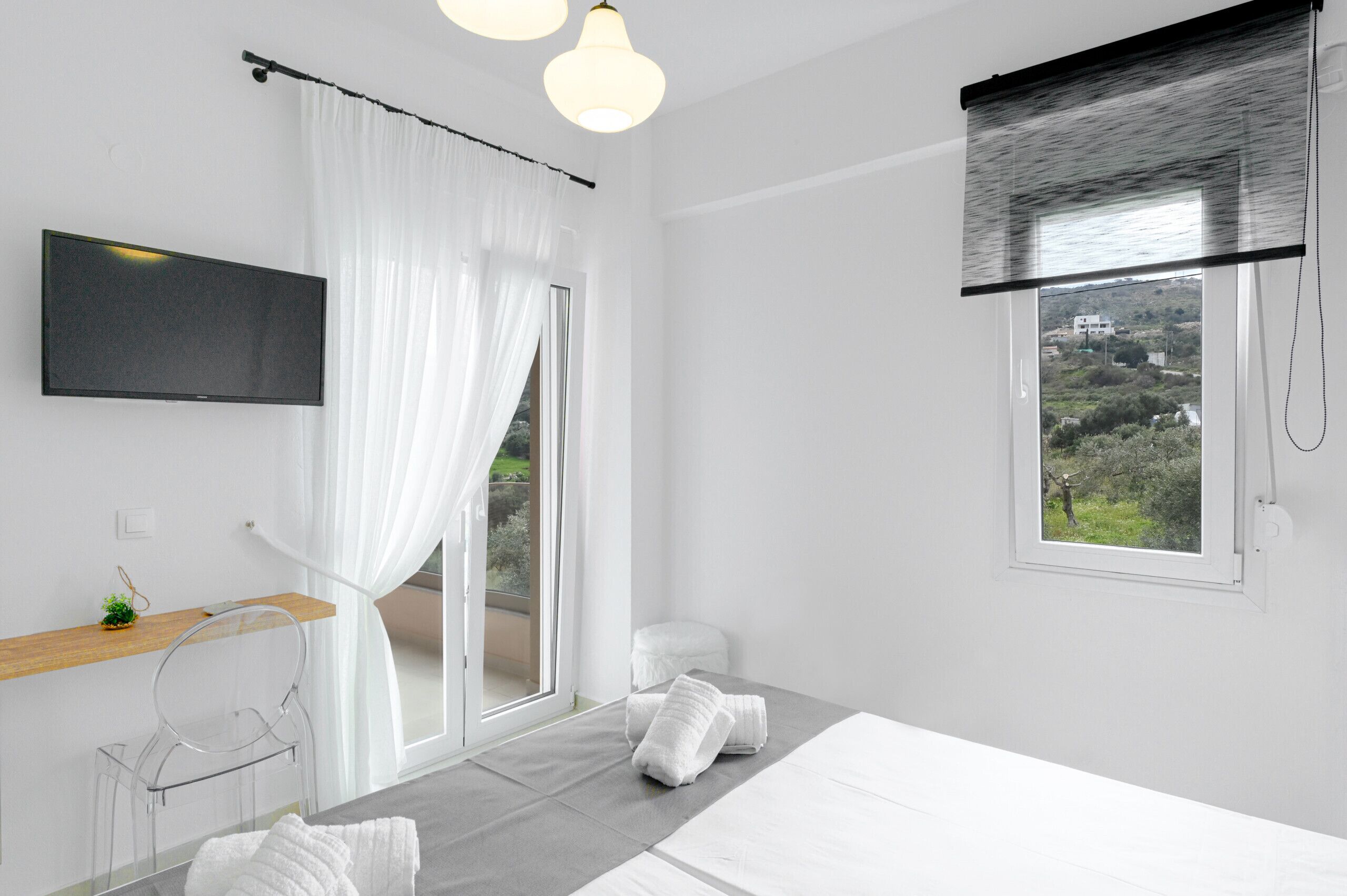 Een moderne slaapkamer met een bed, een televisie, een raam met uitzicht en een badkamer met douchegordijn.
