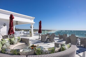 Una terraza en la azotea con mobiliario exterior, una pérgola blanca y vistas al océano.
