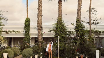 A pool area with palm trees, a building, and a person in swimwear.