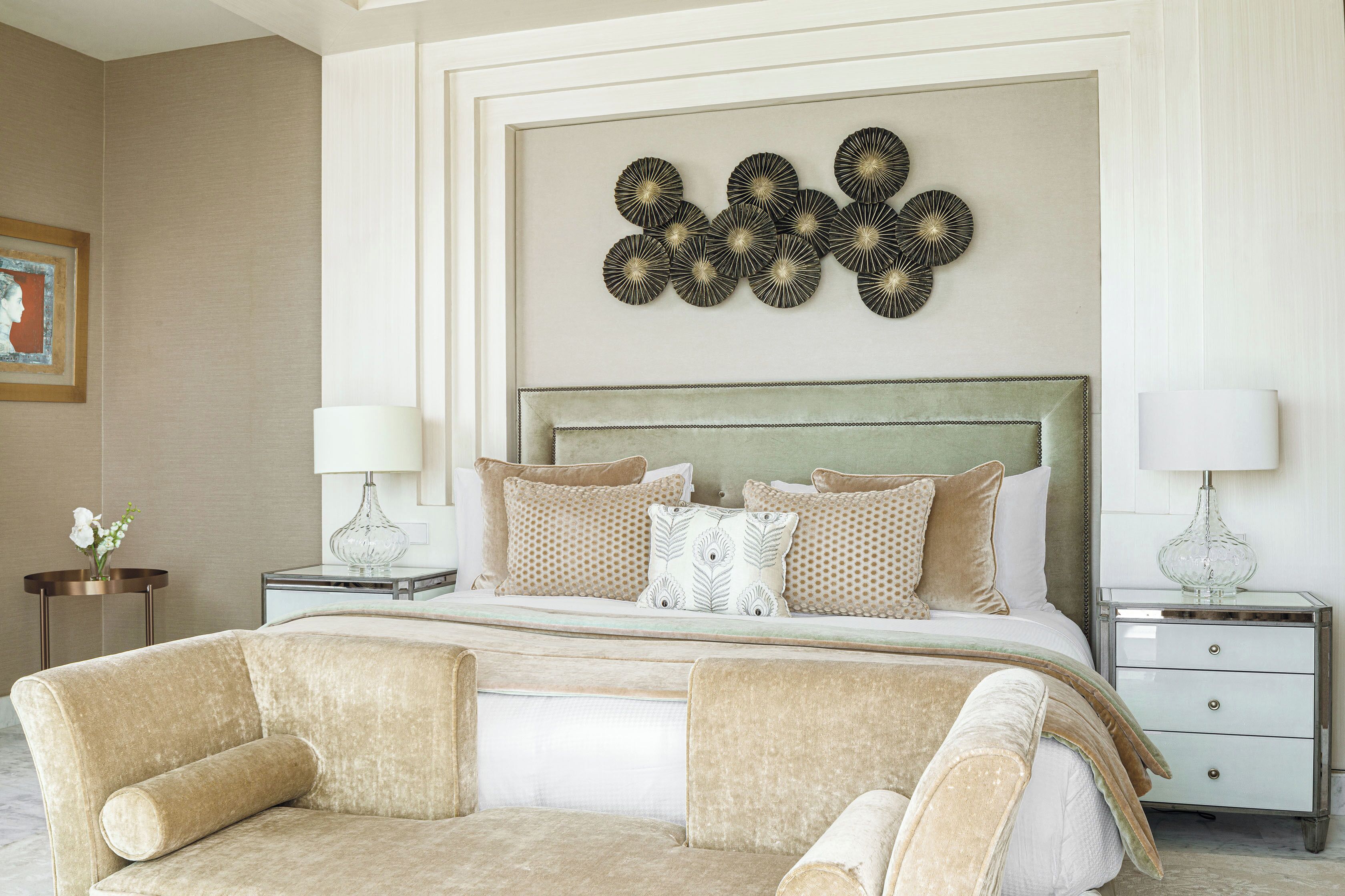 Une chambre élégamment aménagée, dotée d’un grand lit, de deux tables de chevet, d’un élément décoratif mural et d’un tableau encadré accroché au mur.