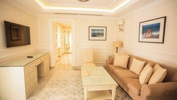 A hotel room with a sofa, a coffee table, a TV, and a painting on the wall.