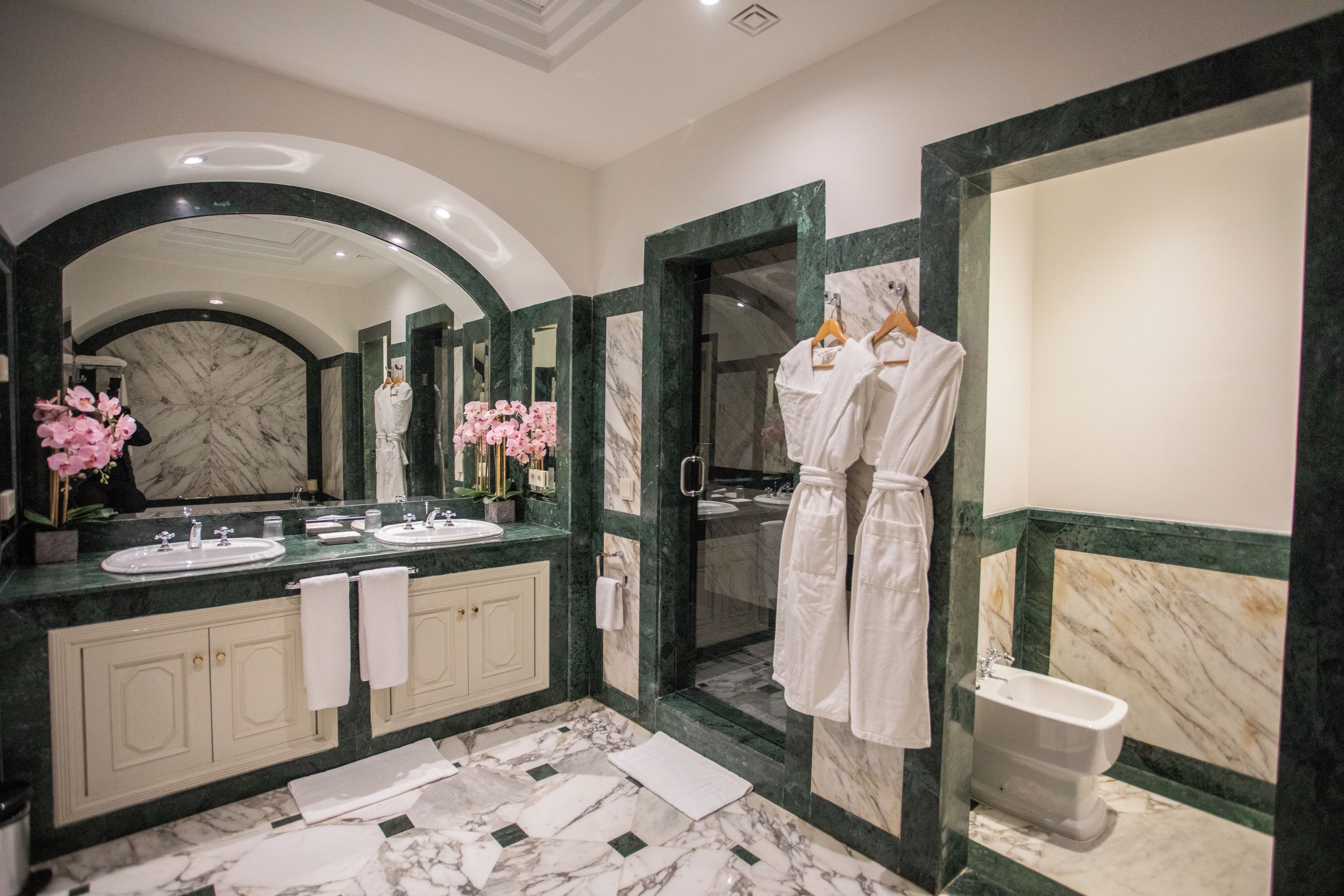 Un baño moderno con un espejo grande, dos lavamanos, una bañera y zona de ducha.