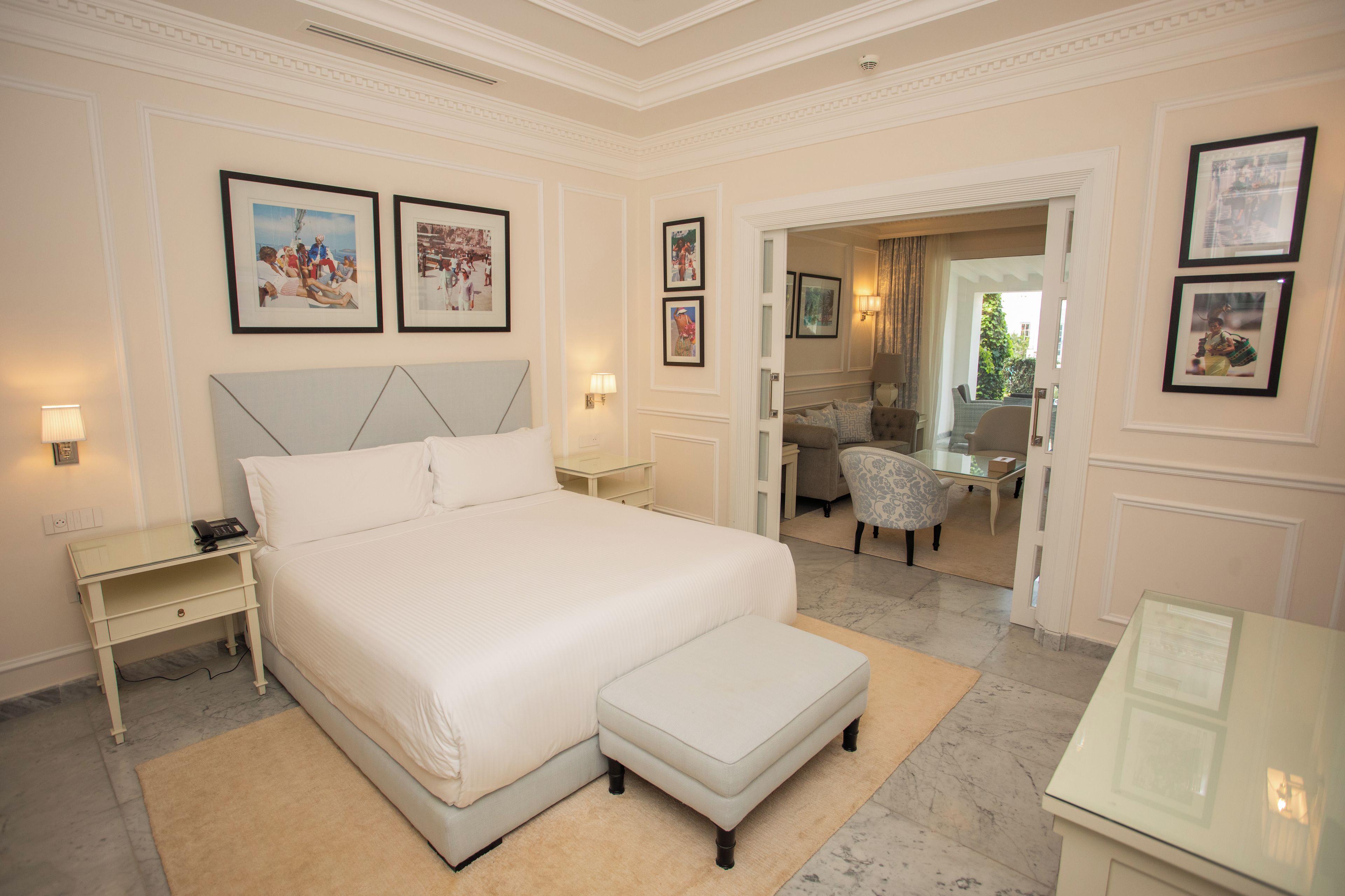 A hotel room with a large bed, a sitting area with a chair, a desk, and a mirror.