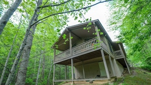 A two-story cabin with a balcony, surrounded by a forested area. - The Bird Hallar - Cozy, quiet cabin in The Glades! (Gatlinburg)
