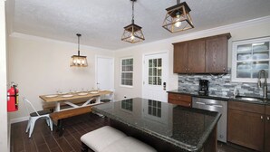 A modern kitchen with a central island, wooden cabinets, and pendant lighting. - Whiskey Ridge - Pet-friendly, Game Tables ,Wi-Fi, Firepit, Rocking Chairs (Sevierville)