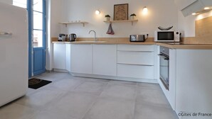 Una cocina moderna con armarios blancos, una puerta azul y un microondas en la encimera.