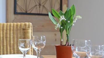 A dining table with a potted plant and four empty wine glasses.
