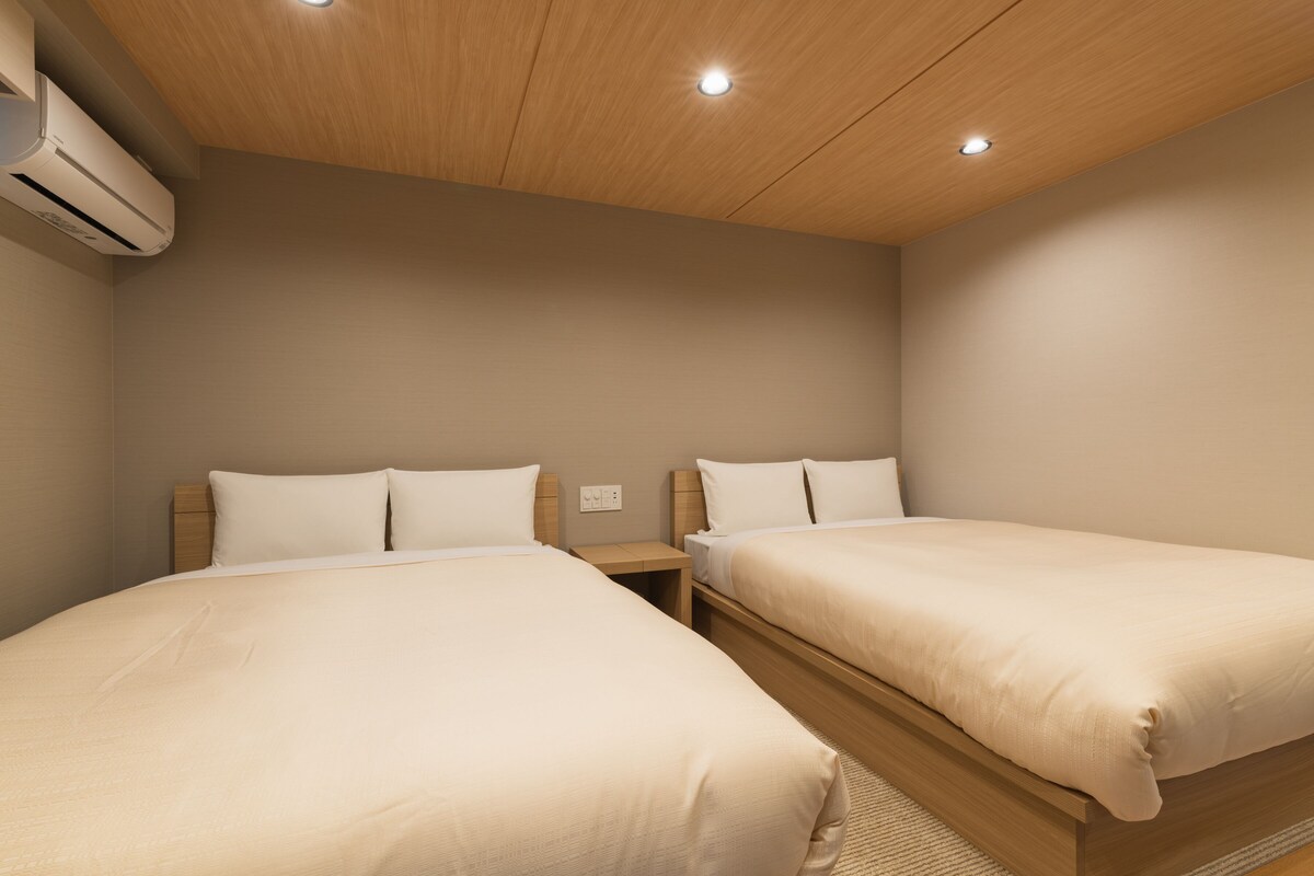 A bedroom with two single beds, wooden headboards, and a ceiling with recessed lighting.