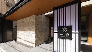 Ein Hotel mit steinverkleideter Fassade, einem Schild mit dem Hotelnamen und einem modernen Design mit Holzbalkendecke.